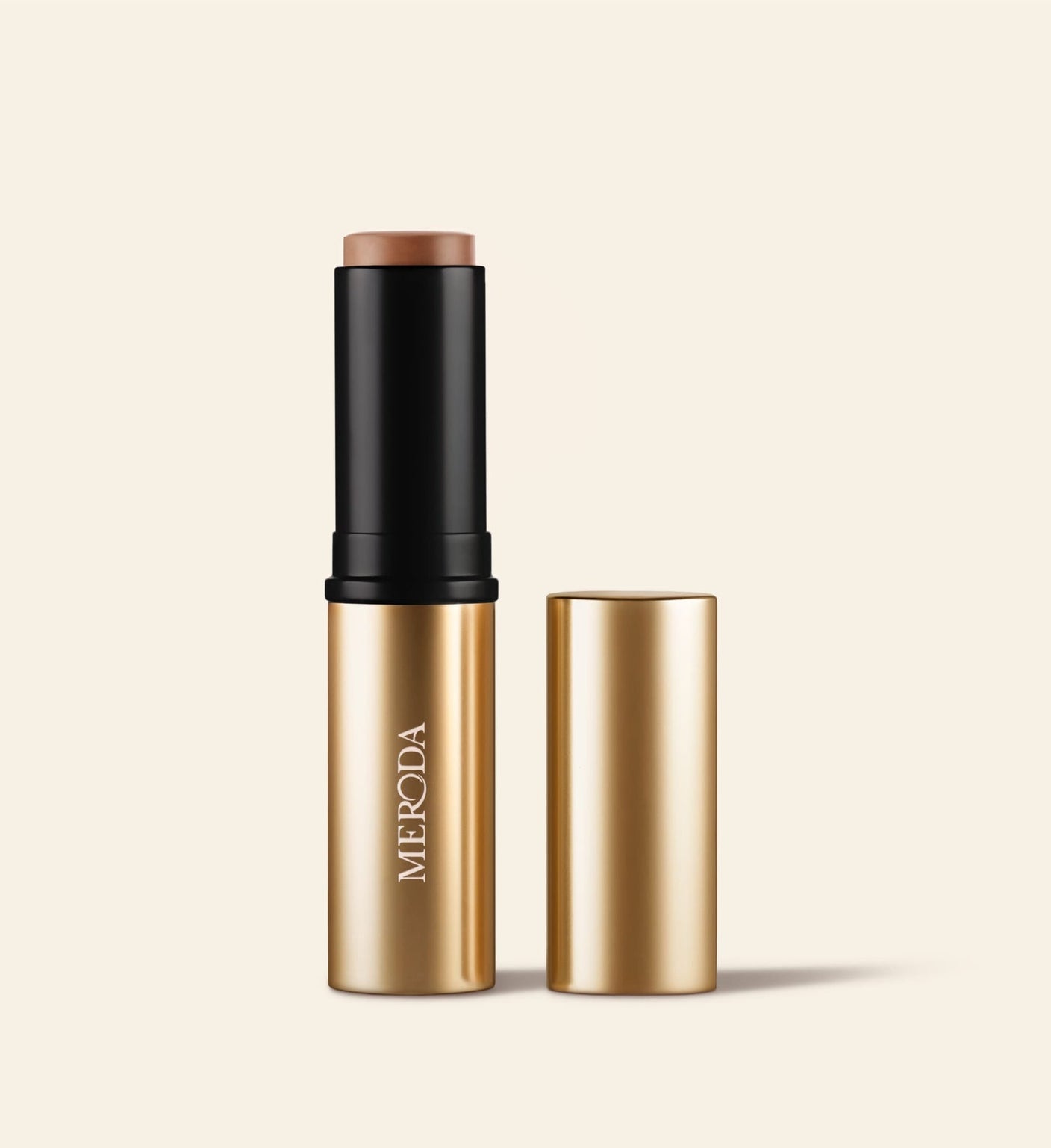 Soft Tan Bronzer in Medium, a creamy bronzer stick shown upright with its matching gold metallic cap beside it.
