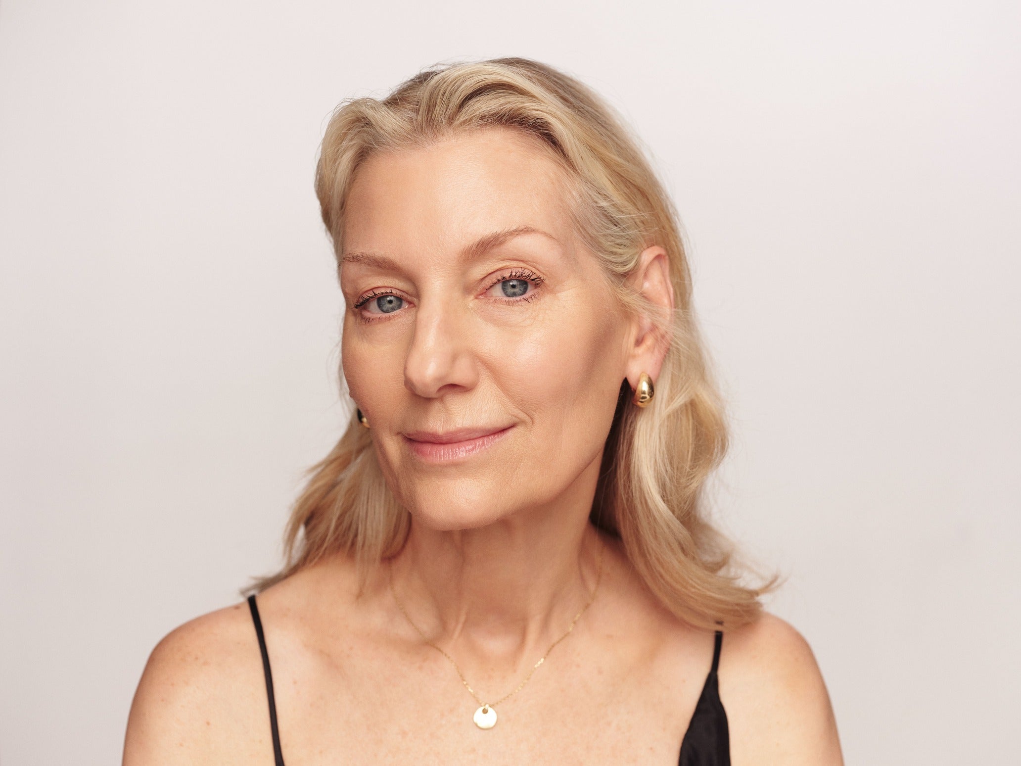 Woman with blonde hair and a neutral expression against a plain background