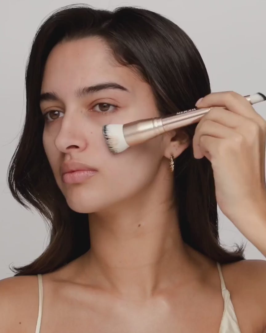Model blending foundation with the 2-in-1 Build & Conceal Brush for a flawless complexion.