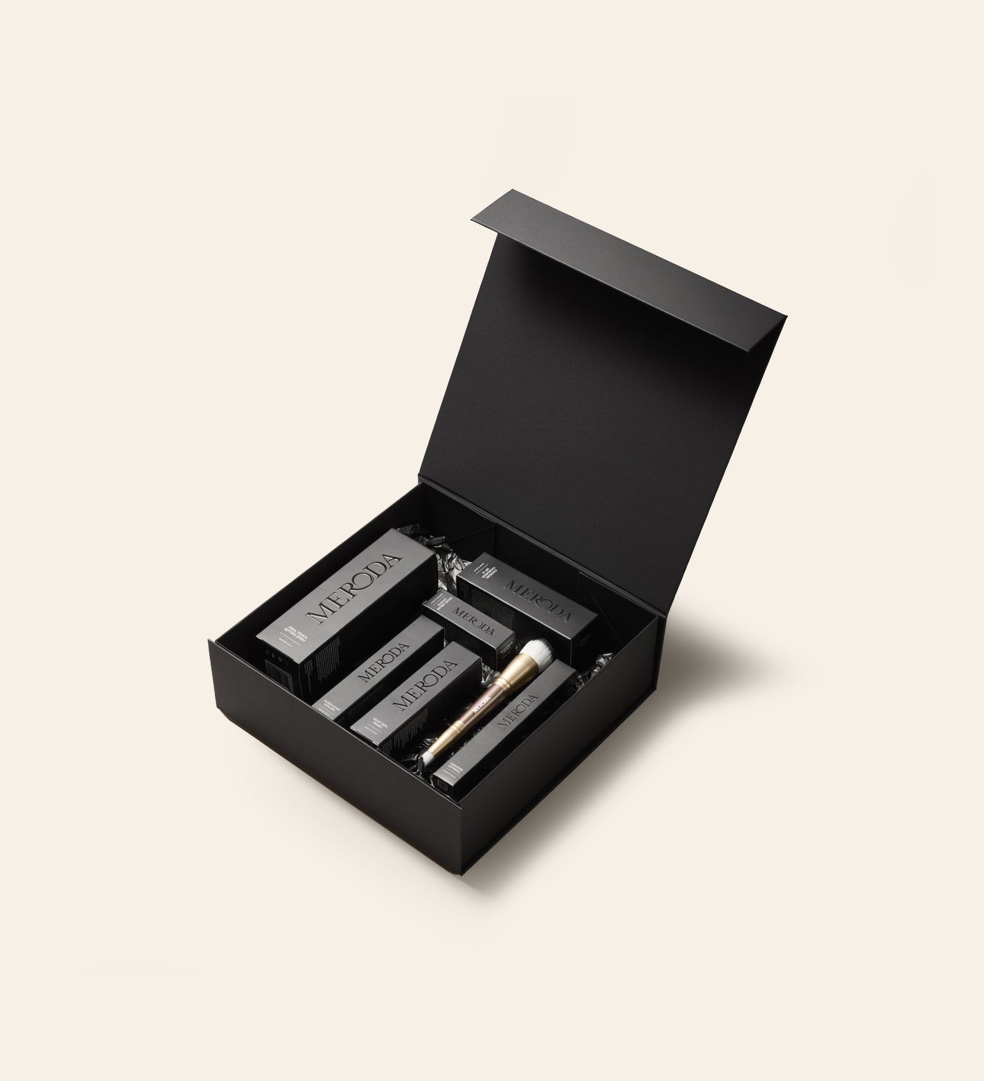 Matte black Gift Box with magnetic closure filled with Meroda Cosmetics and a gold makeup brush.