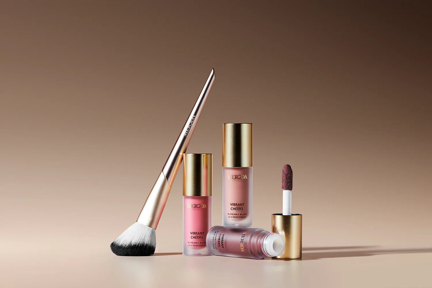 Vibrant Cheeks Blush Brush with synthetic bristles and gold handle alongside three Vibrant Cheeks Liquid Blush bottles.