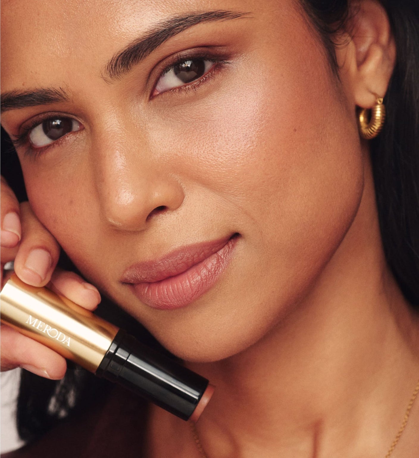 Soft Tan Bronzer in shade Dark held by model for a natural, sun-kissed glow and radiant finish.