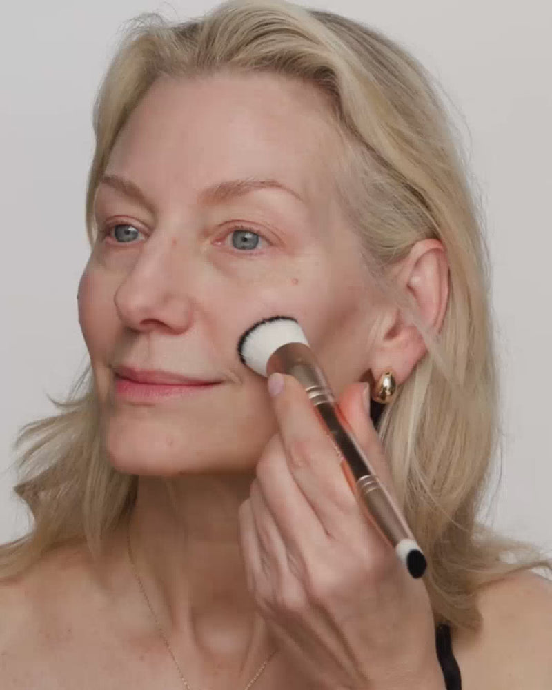 Mature woman blending Changing Foundation with a 2-in-1 brush to reveal its colour-adapting finish.